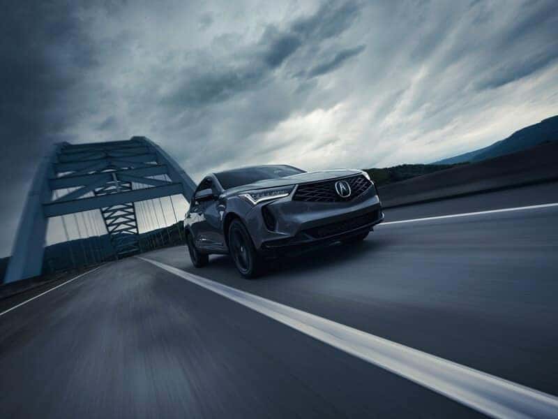 Tilted image of gray Acura RDX in front of a bridge