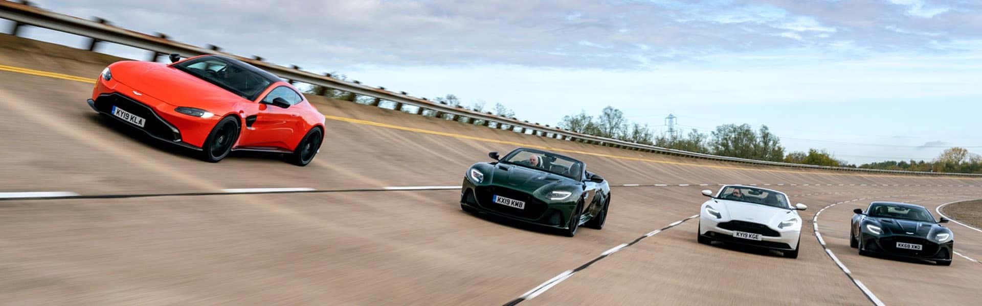 Four Aston Martin cars on a race track.