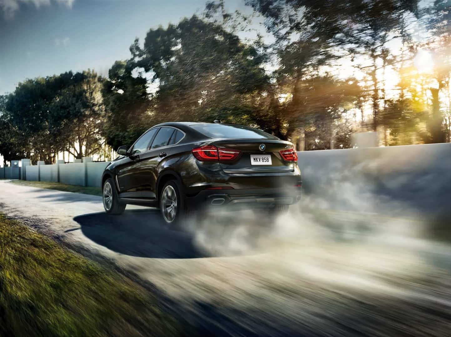 BMW X6 driving down road from the back