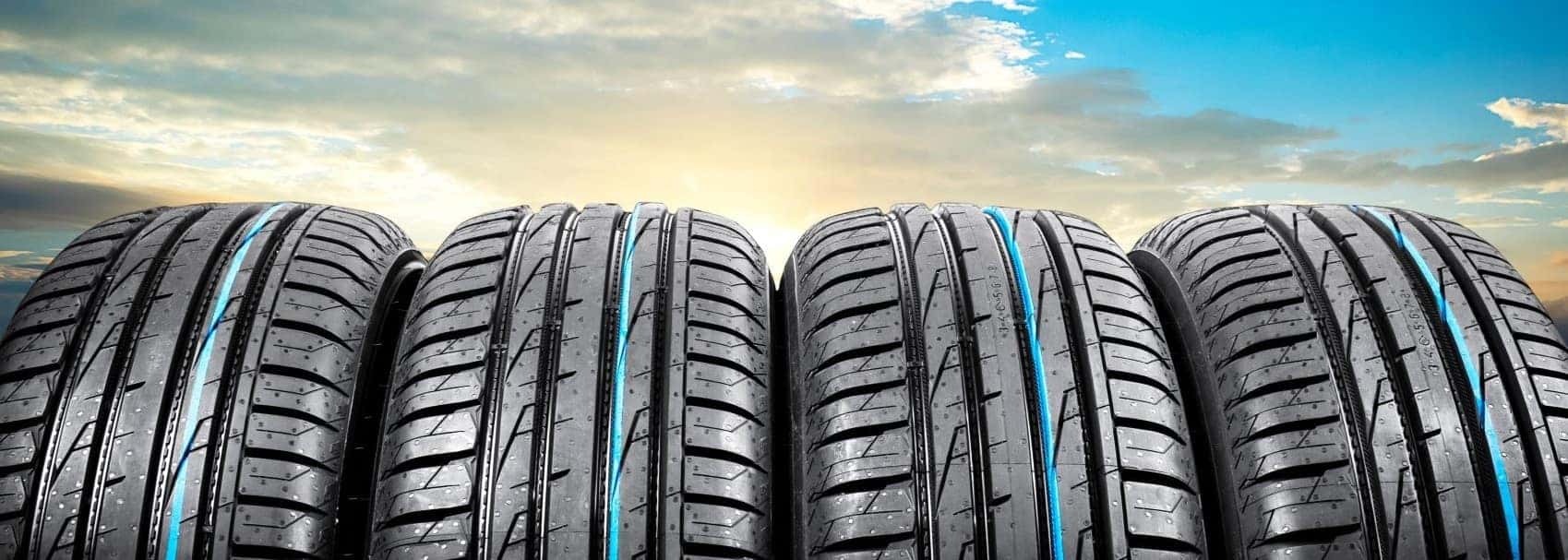 Row of tires in front of blue sky with clouds