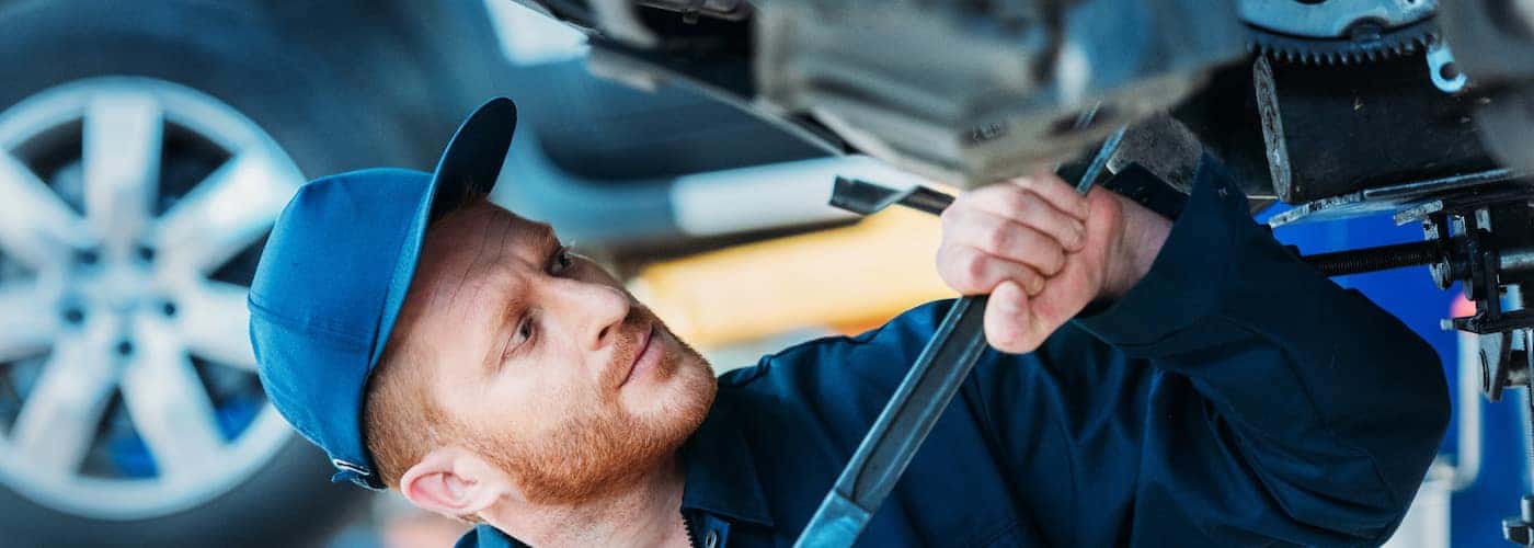 mechanic working under car with large wrench close up