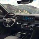 Interior view of the infotainment system, dashboard, and steering wheel inside the 2025 Hyundai Tucson Hybrid for sale in Waukesha WI