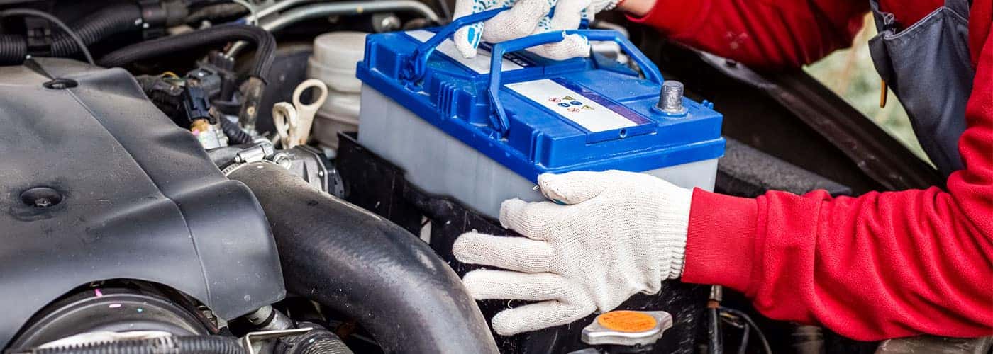 technician installing a new battery in a car