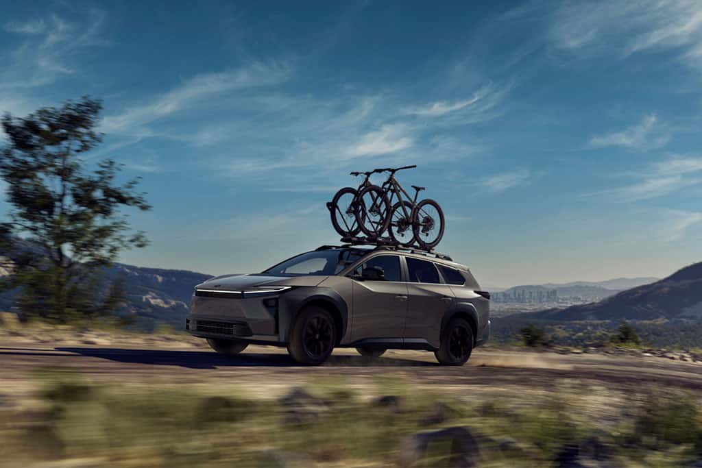 2026 Toyota bZ Woodland in grey color driving offroad with roof rails and two bikes mounted on top