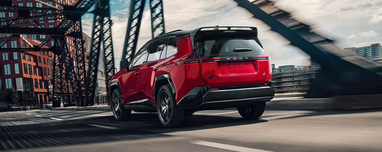 2026 Toyota RAV4 Plug-In Hybrid GR Sport in red driving in an urban area showing backside