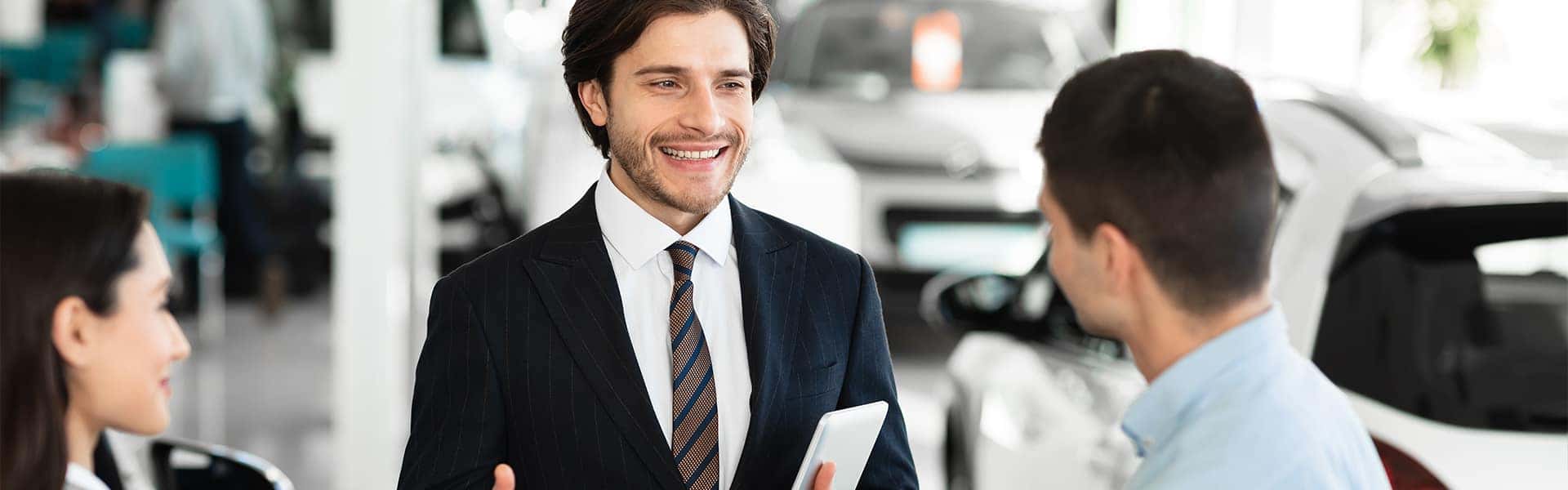 Selling your vehicle with Carolina Chrysler, Dodge, Jeep, and RAM in Elizabeth City instead of the other guy | Sales Advisor Talking to Two Customers on Sales Floor