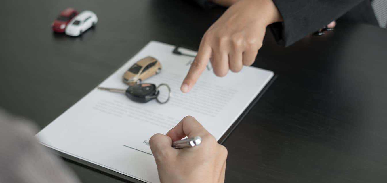 Defining GAP Insurance at Carolina Chrysler Dodge Jeep & RAM in Elizabeth City, NC | Customer Filling out Paperwork for Insurance