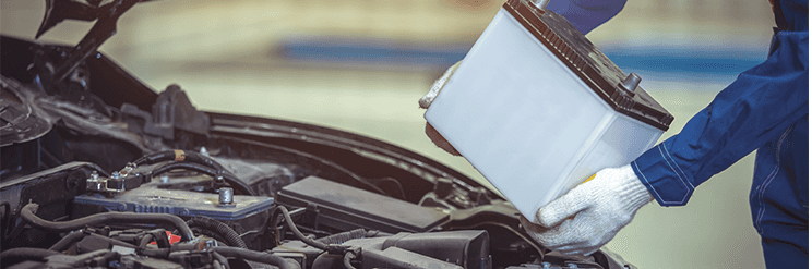 Everything You Need to Know about Your Car Battery at Carolina CDJR | Person in blue uniform and white gloves putting a new battery into the engine bay
