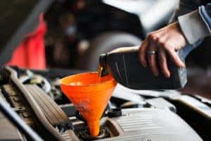 Technician pouring oil into oil reservoir on a vehicle 