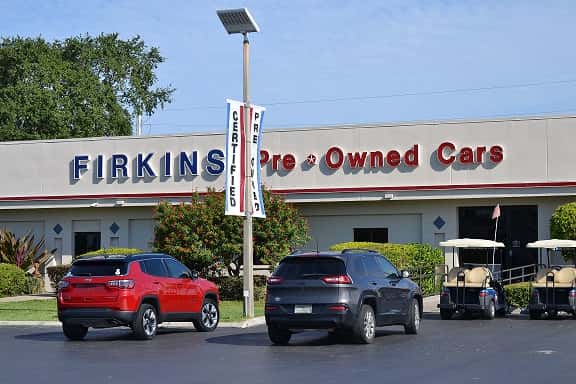 vehicles parked in front of the Firkins Preowned Car building
