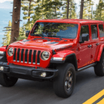 Red Used Jeep Wrangler driving on the road