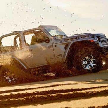 2020 Jeep Wrangler driving off road in a cloud of dust