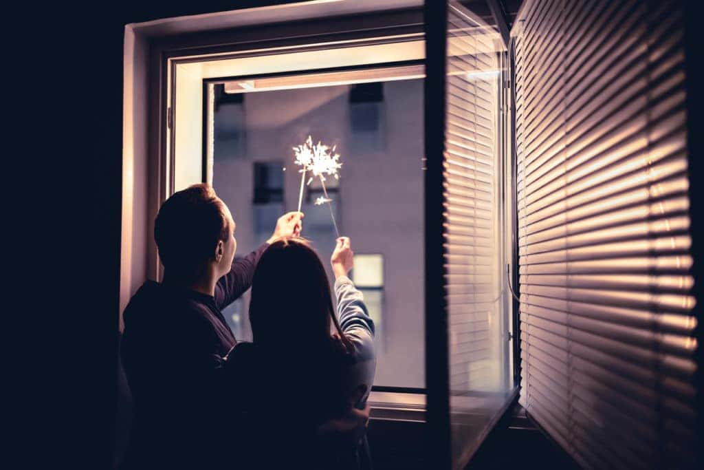 Couple holding sparklers out of the window at New year's eve