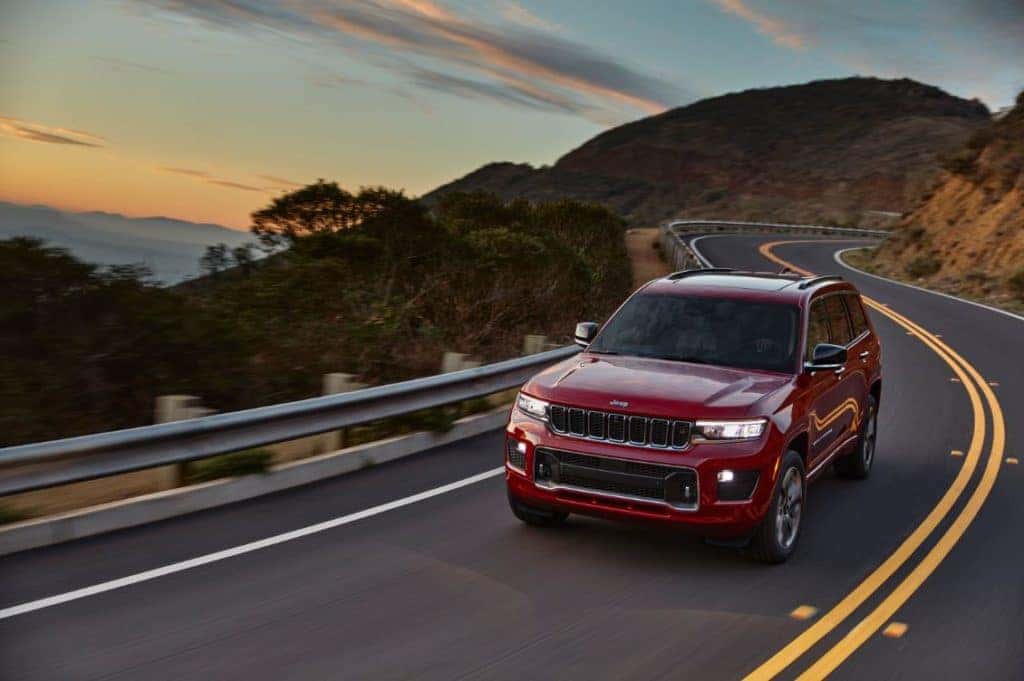 red SUV on cliffside road at sunset