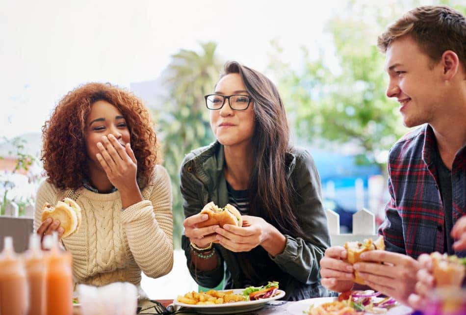 Cropped shot of three friends eating burgers
