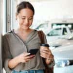 young woman texting while car shopping