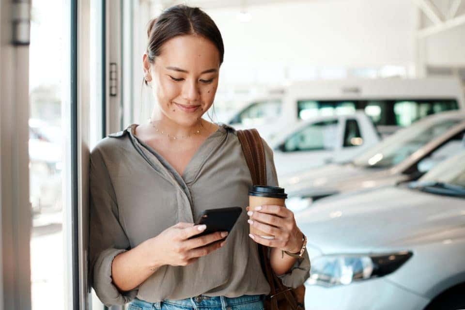 young woman texting while car shopping