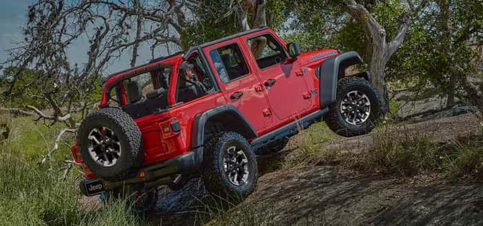 Red 2025 Jeep Wrangler driving over rocks