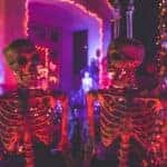 Two skeleton near white concrete building with string lights at daytime