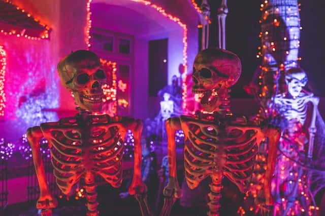 Two skeleton near white concrete building with string lights at daytime