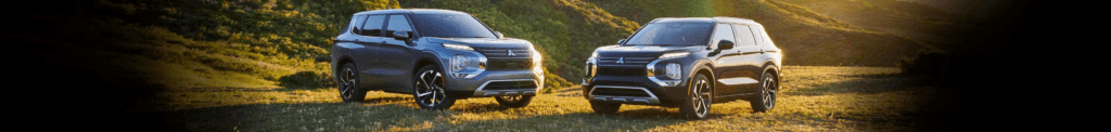 Two 2023 Mitsubishi Oulander facing each other in a field