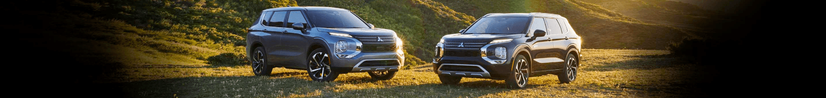 Two 2023 Mitsubishi Oulander facing each other in a field