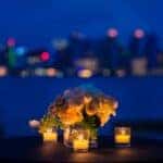 white rose bouquet in vase with three tealight candle votives on round brown wooden table
