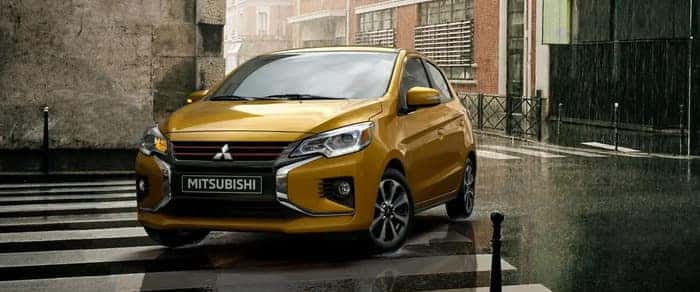 Yellow 2024 Mitsubishi Mirage driving in the rain