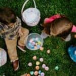 Girl in green jacket with white and pink plastic balls on green grass field