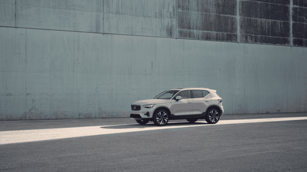 Side profile of the 2025 Volvo XC40 parked along a concrete urban wall, highlighting its compact luxury SUV design.