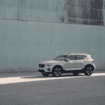 Side profile of the 2025 Volvo XC40 parked along a concrete urban wall, highlighting its compact luxury SUV design.