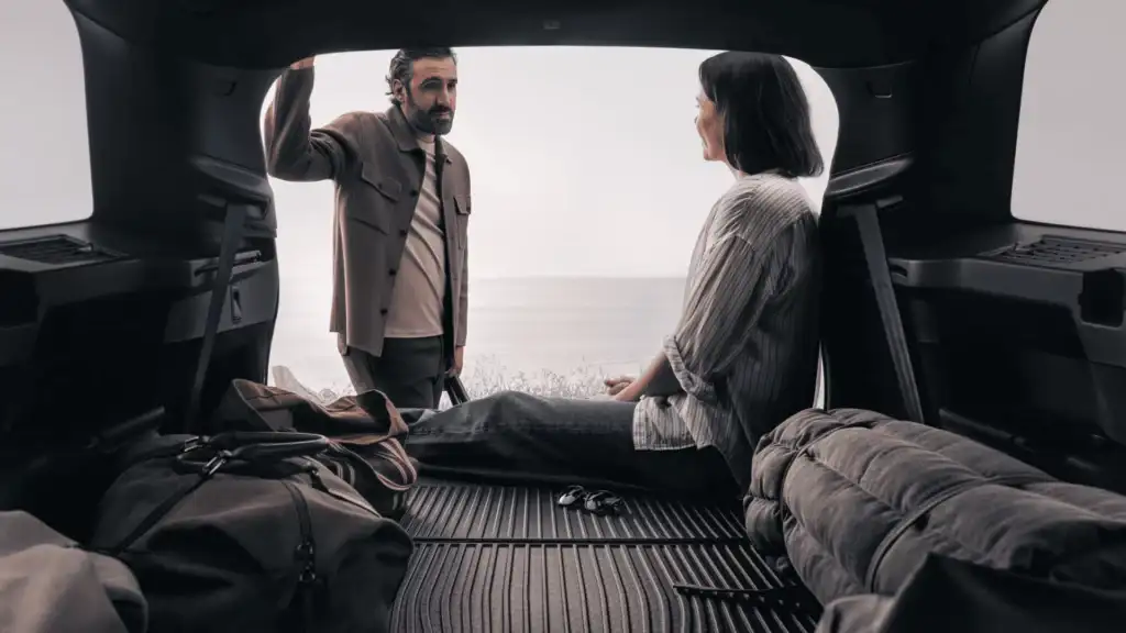 Interior view of the 2025 Volvo XC90 with passengers relaxing in the cargo space, highlighting comfort and versatility.