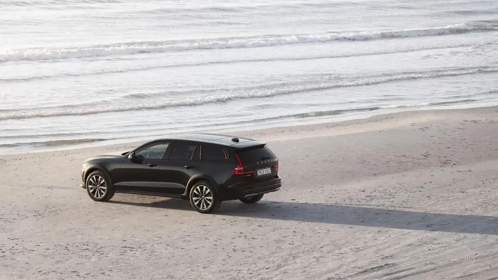 2026 Volvo V60 Cross Country wagon in black driving on sandy beach near ocean showcasing all-road capability near Johnson City TN
