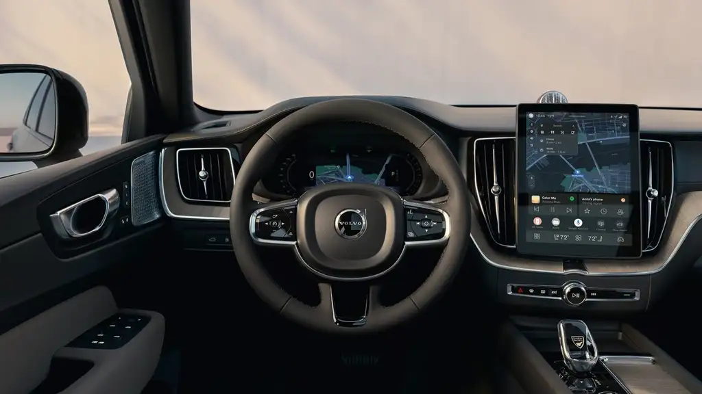 2026 Volvo XC60 interior cockpit with vertical touchscreen infotainment showing navigation and media, digital gauge cluster, and premium dark cabin