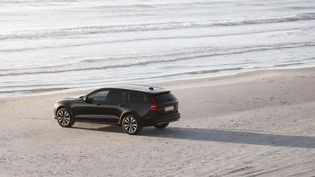 2026 Volvo V60 Cross Country wagon in black parked on sandy beach with ocean waves in background near Asheville NC