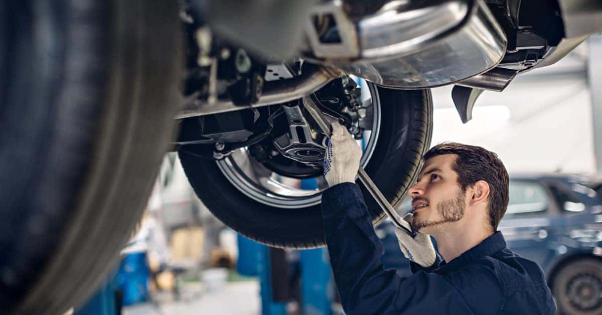 a mechanic checking the underside of a car