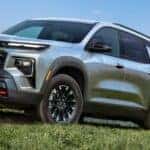 Gray 2024 Chevy Traverse Front and Side Exterior on a Grassy Hill