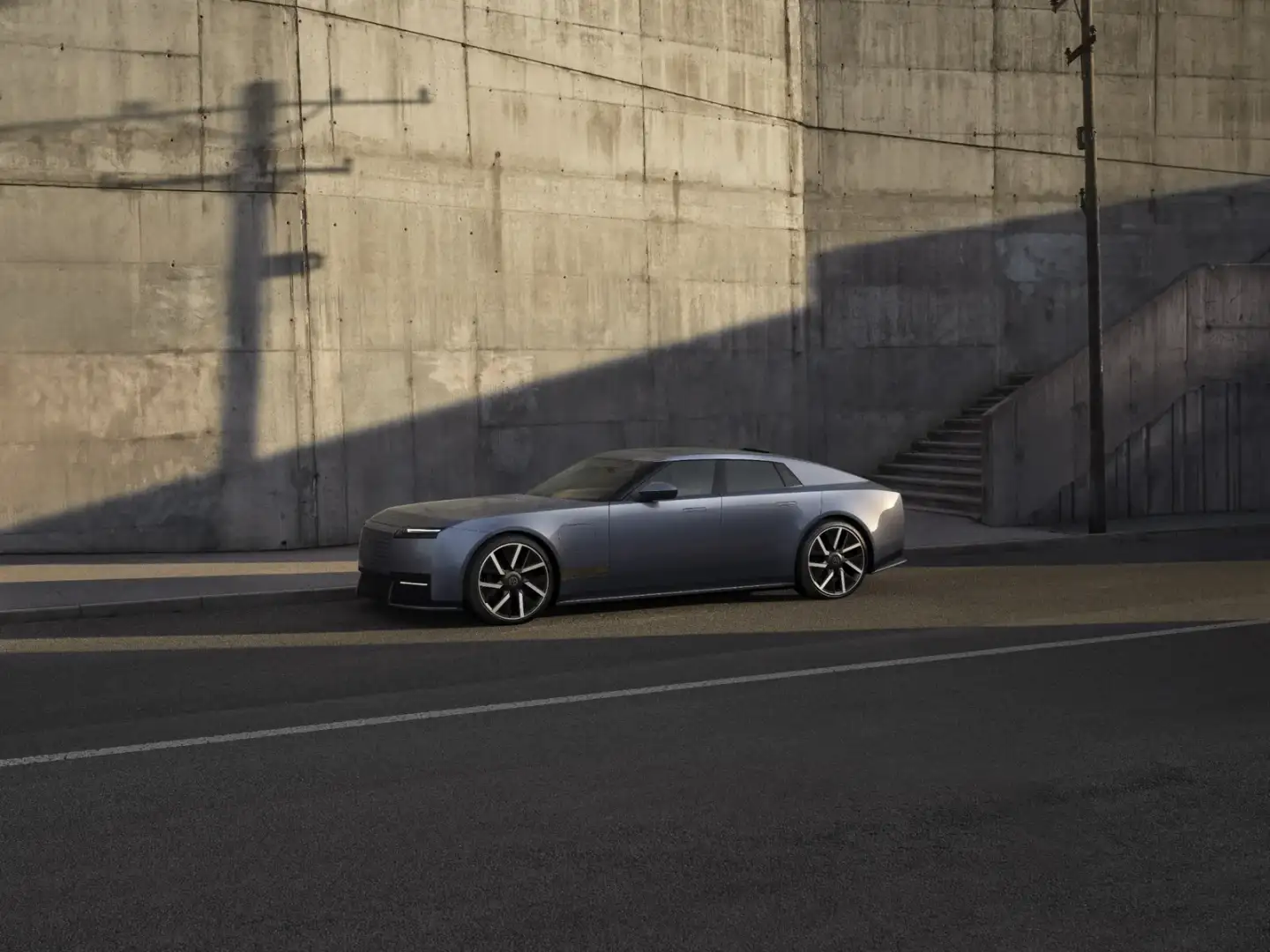 Side profile of a blue Jaguar Type 01 electric four-door GT against a concrete wall