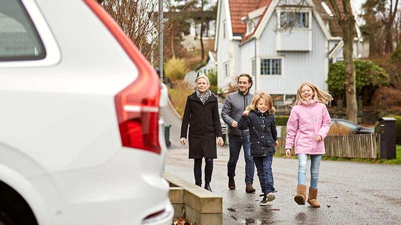 A famly of 4 walking towards their Volvo vehicle