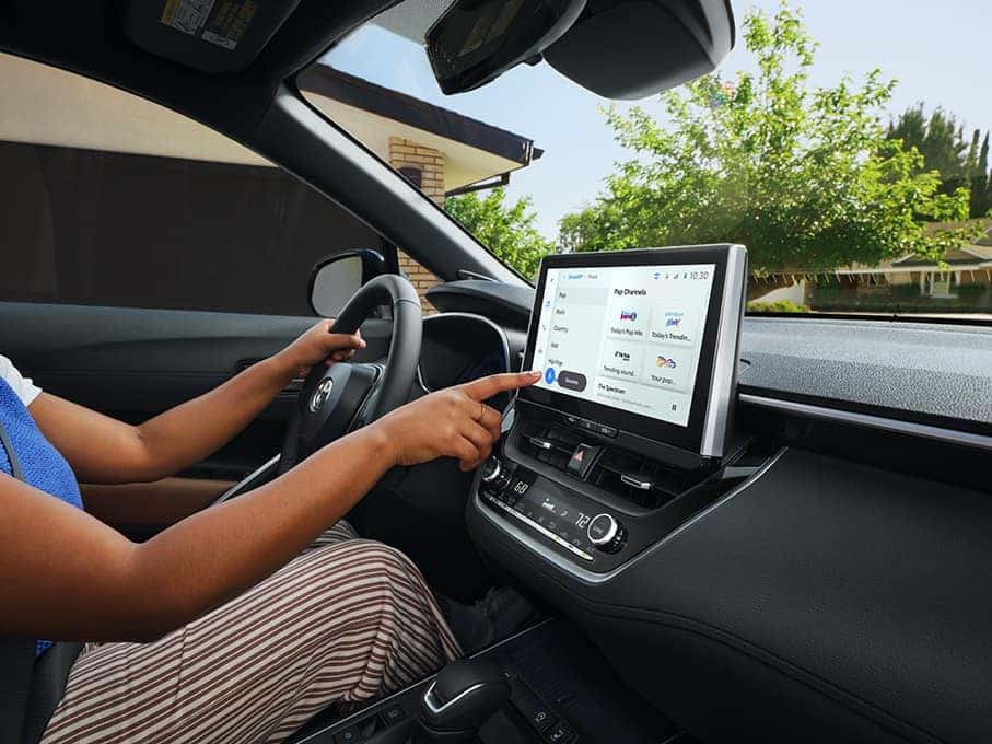 Driver using the multimedia touchscreen in the 2026 Toyota Corolla Cross at Joseph Airport Toyota in Vandalia, Ohio