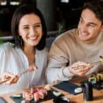 Happy couple eating sushi with chopsticks