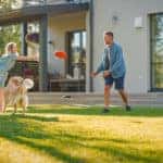 Family of Four Play Fetch flying disc with Happy Golden Retriever Dog on the Backyard Lawn