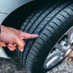 A human hand checking a tire tread