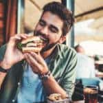 Young man sitting in a cafe and enjoying in breakfast.