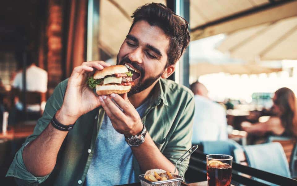 Young man sitting in a cafe and enjoying in breakfast.