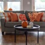 Home interior decorated for fall with orange accent pillows on the sofa