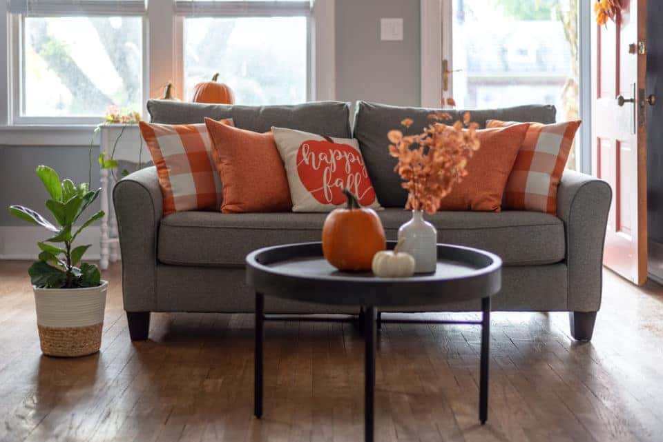 Home interior decorated for fall with orange accent pillows on the sofa