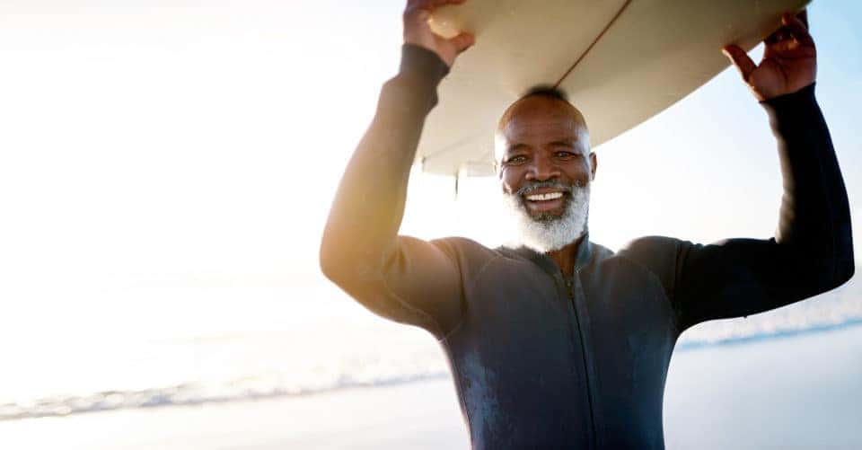 Shot of a mature man carrying a surfboard at the beach