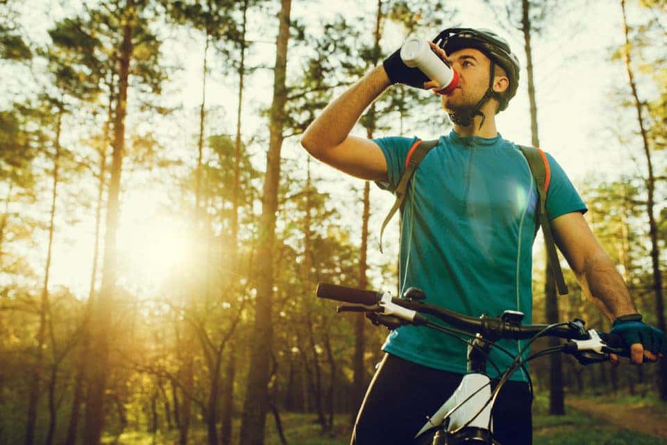 Handsome young professional cyclist dressed in cycling clothing and protective helmet