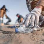 Volunteer man collecting trash on the beach.